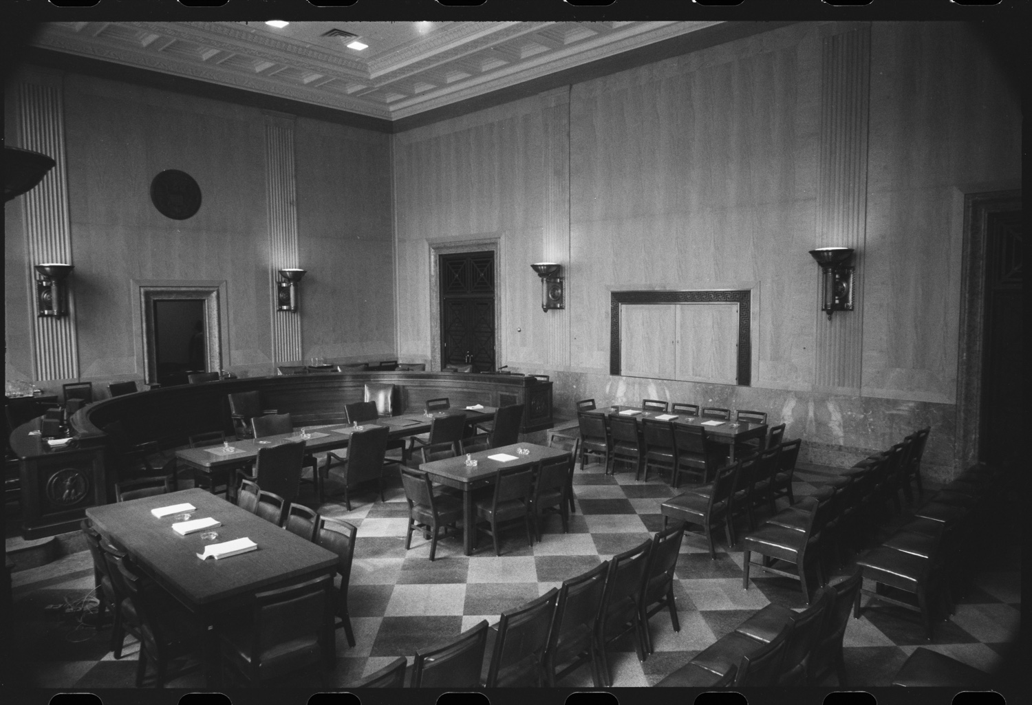 An empty wood-paneled Senate committee hearing room with a raised dais and witness tables.