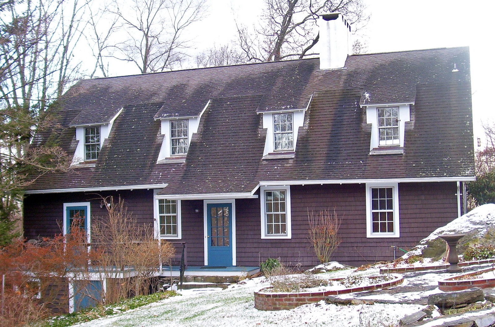 A brown-shingled two-story house among bare winter trees in Katonah, New York.