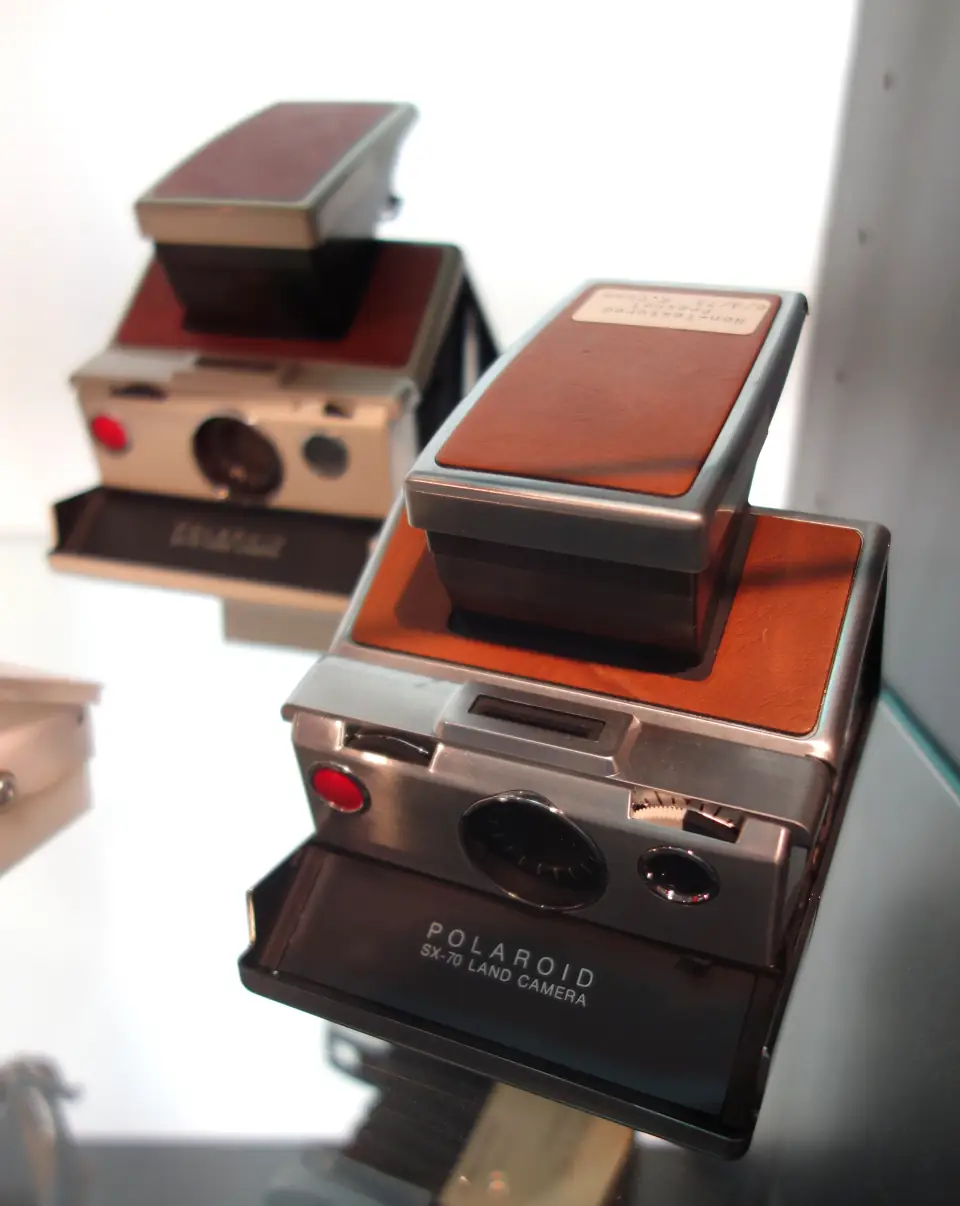 A Polaroid SX-70: the flat folding chrome-and-leather instant camera, opened into its angular shooting position.