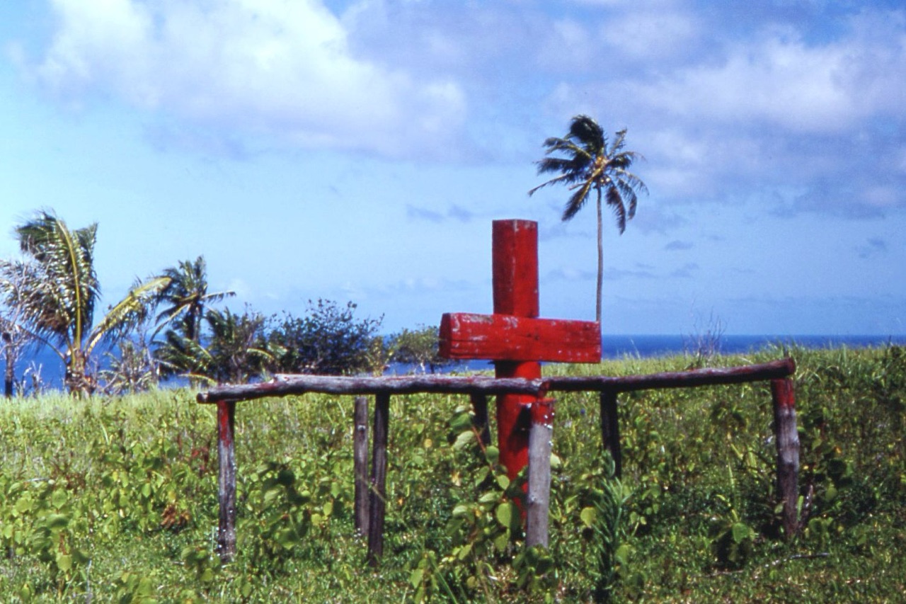 A tall red wooden cross standing in a clearing on Tanna island, the sacred symbol of the John Frum movement.