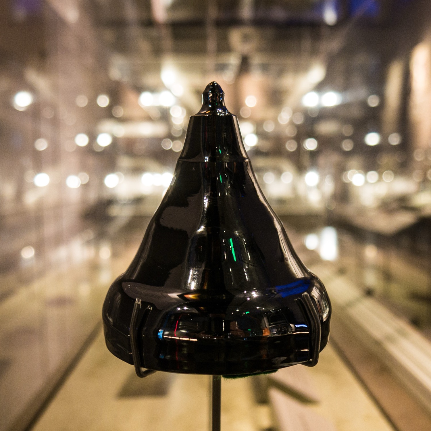 A mirror-black cylinder of pure silicon, a grown single crystal with a tapered seed neck on top, glowing against a dark background.