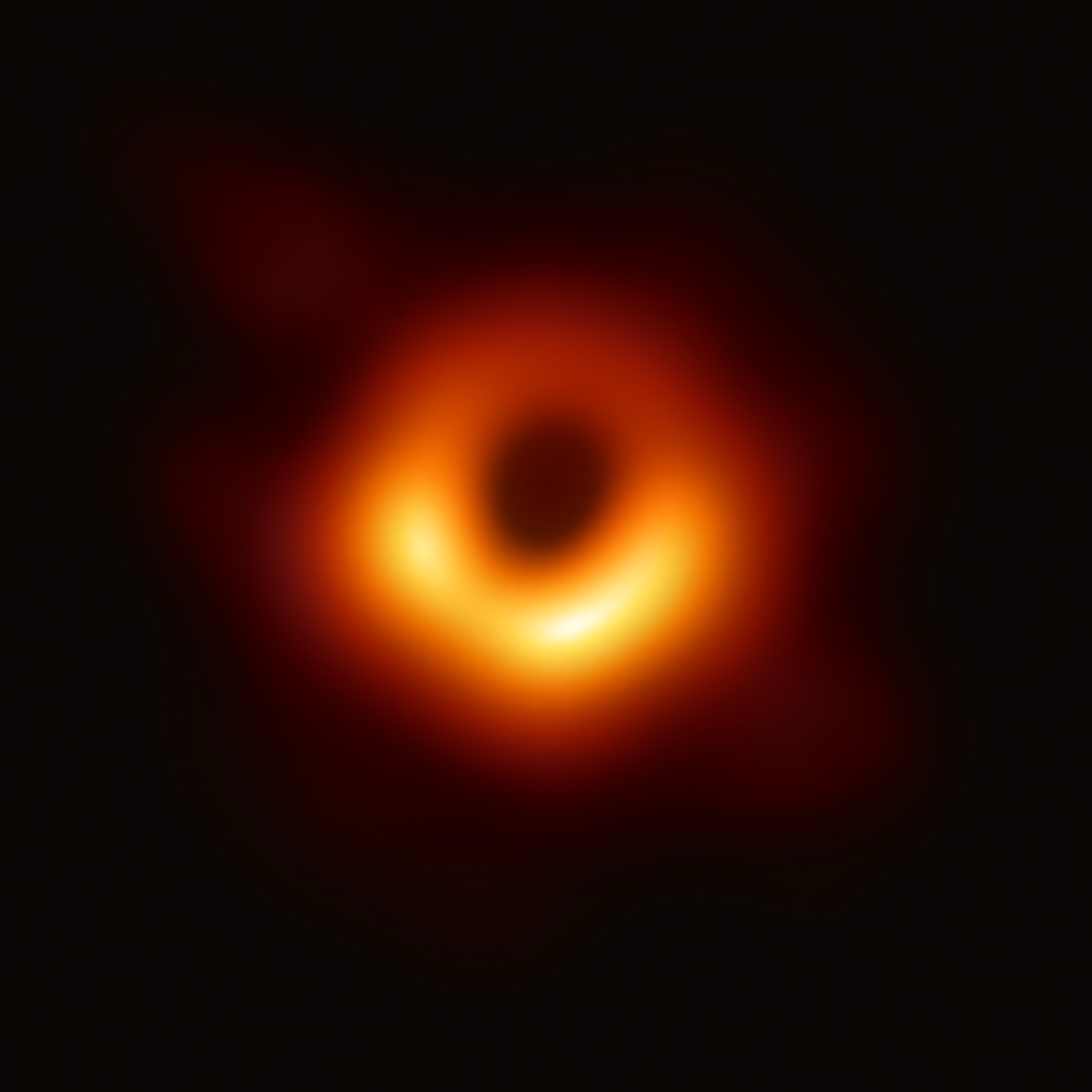 The 2019 Event Horizon Telescope image of the M87 black hole: a fuzzy bright orange ring of glowing gas surrounding a dark central shadow.
