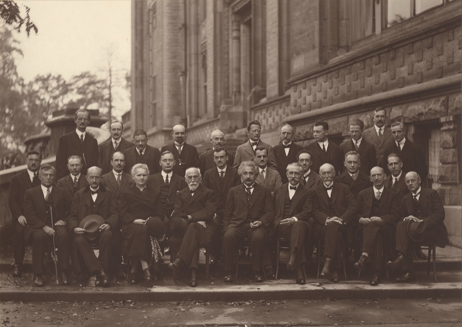 The 1927 Solvay Conference group photograph: 29 physicists in formal dress arranged in three rows, including Einstein seated front-center, with Marie Curie, Niels Bohr, Max Planck, Erwin Schrodinger, Werner Heisenberg and Paul Dirac.