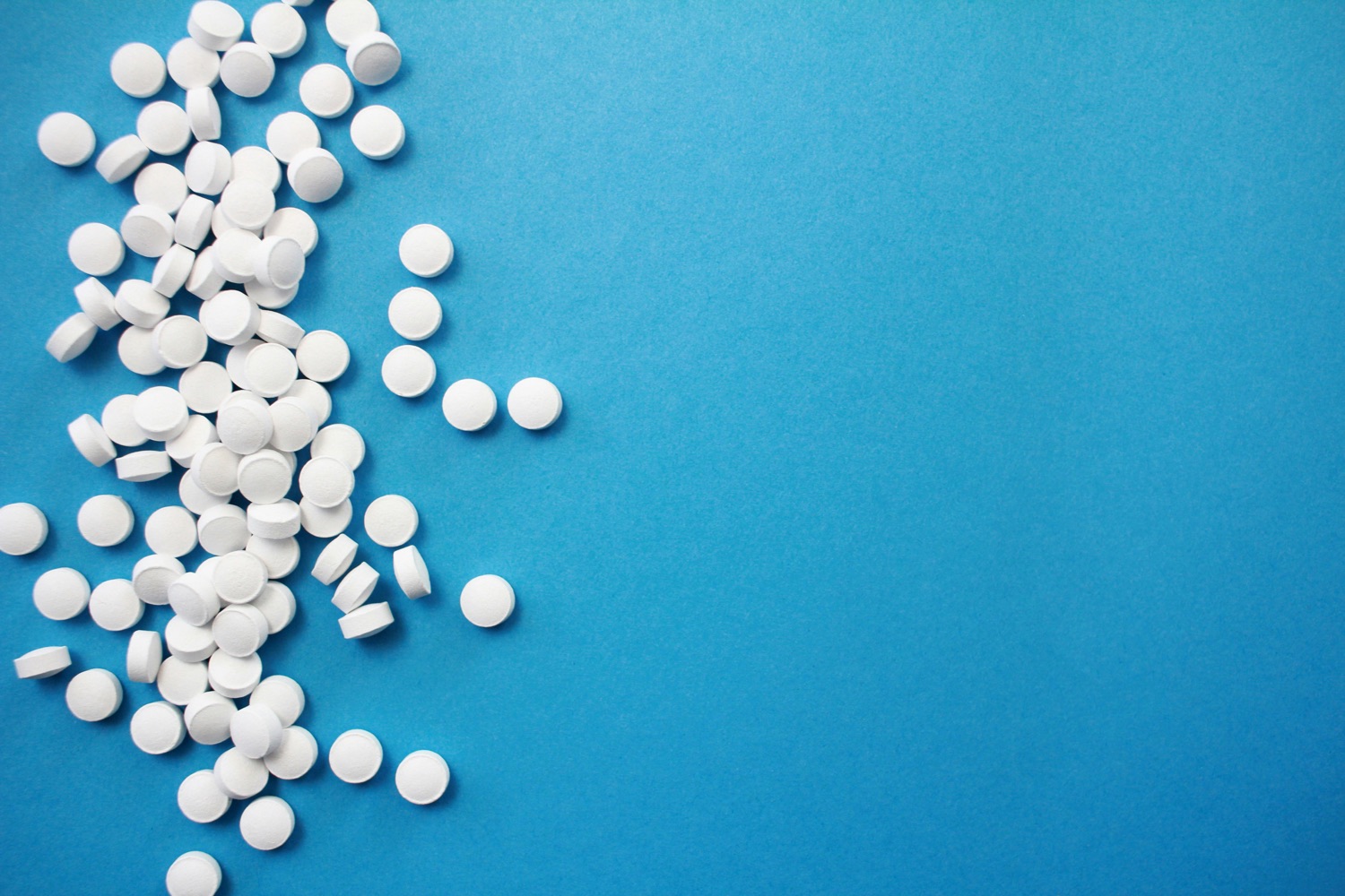 A scatter of plain round white pills on a clean surface.