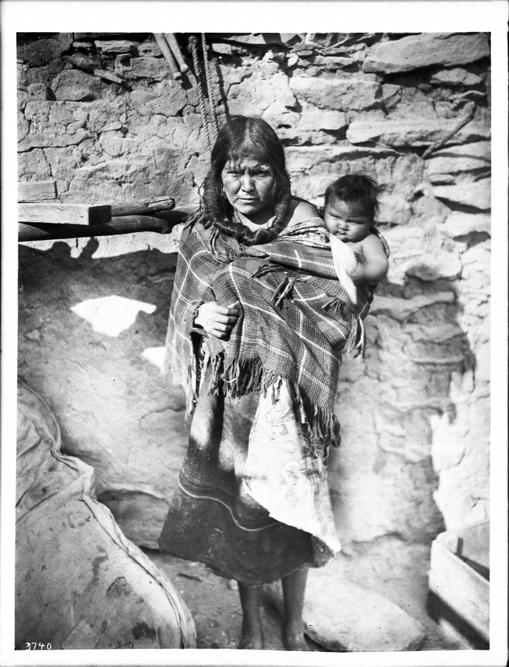 A Hopi mother around 1900 carrying her baby on her back in a woven wrap.