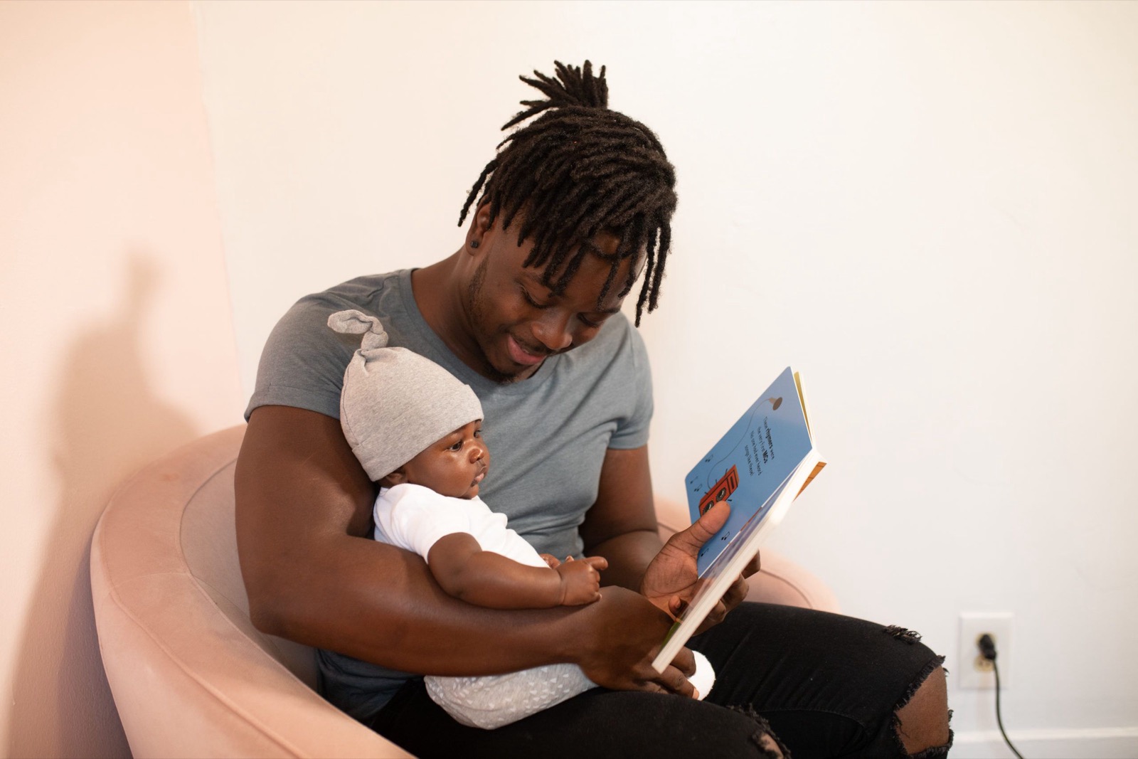 A father sitting and reading a board book to his baby.