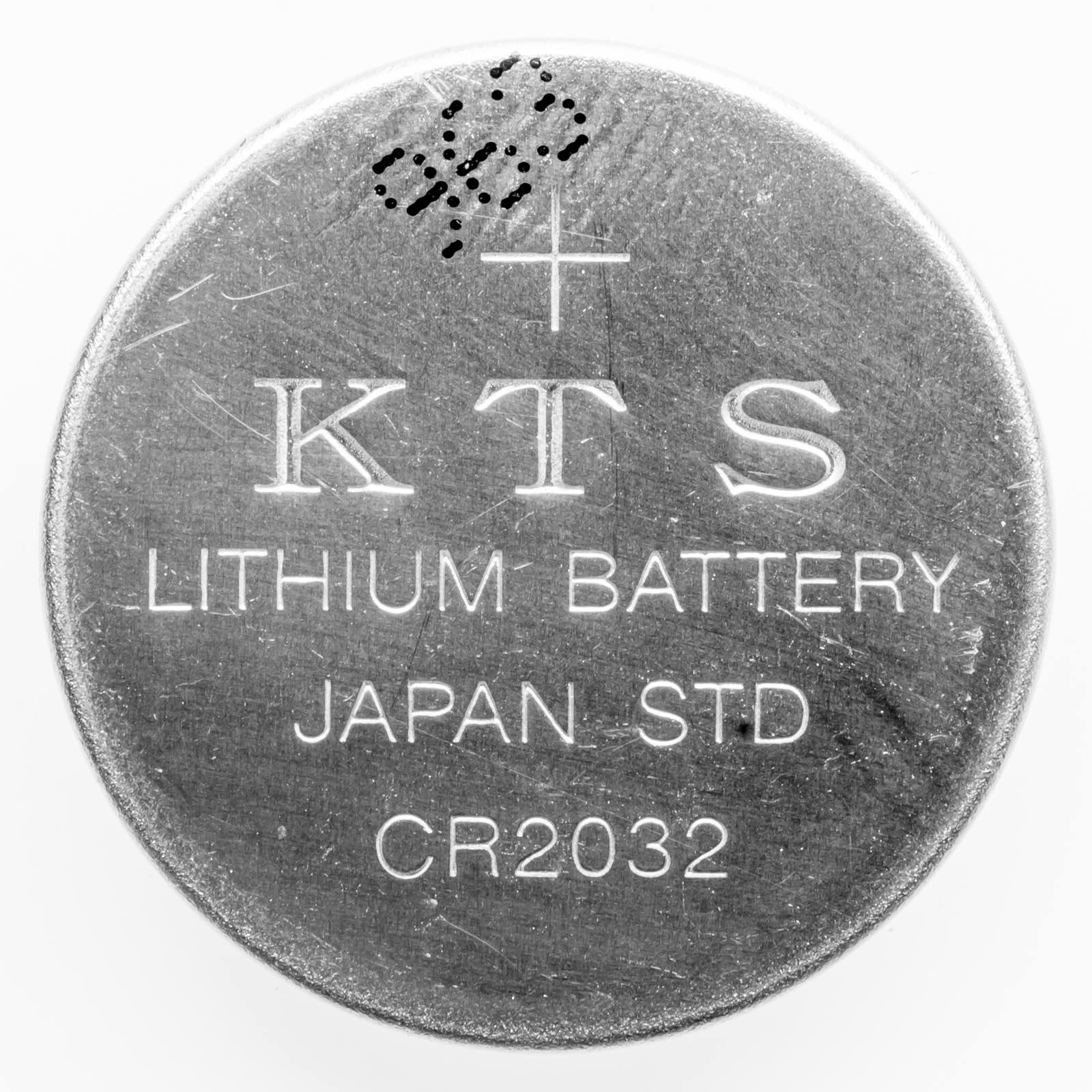 A close-up of a single round lithium coin-cell button battery.