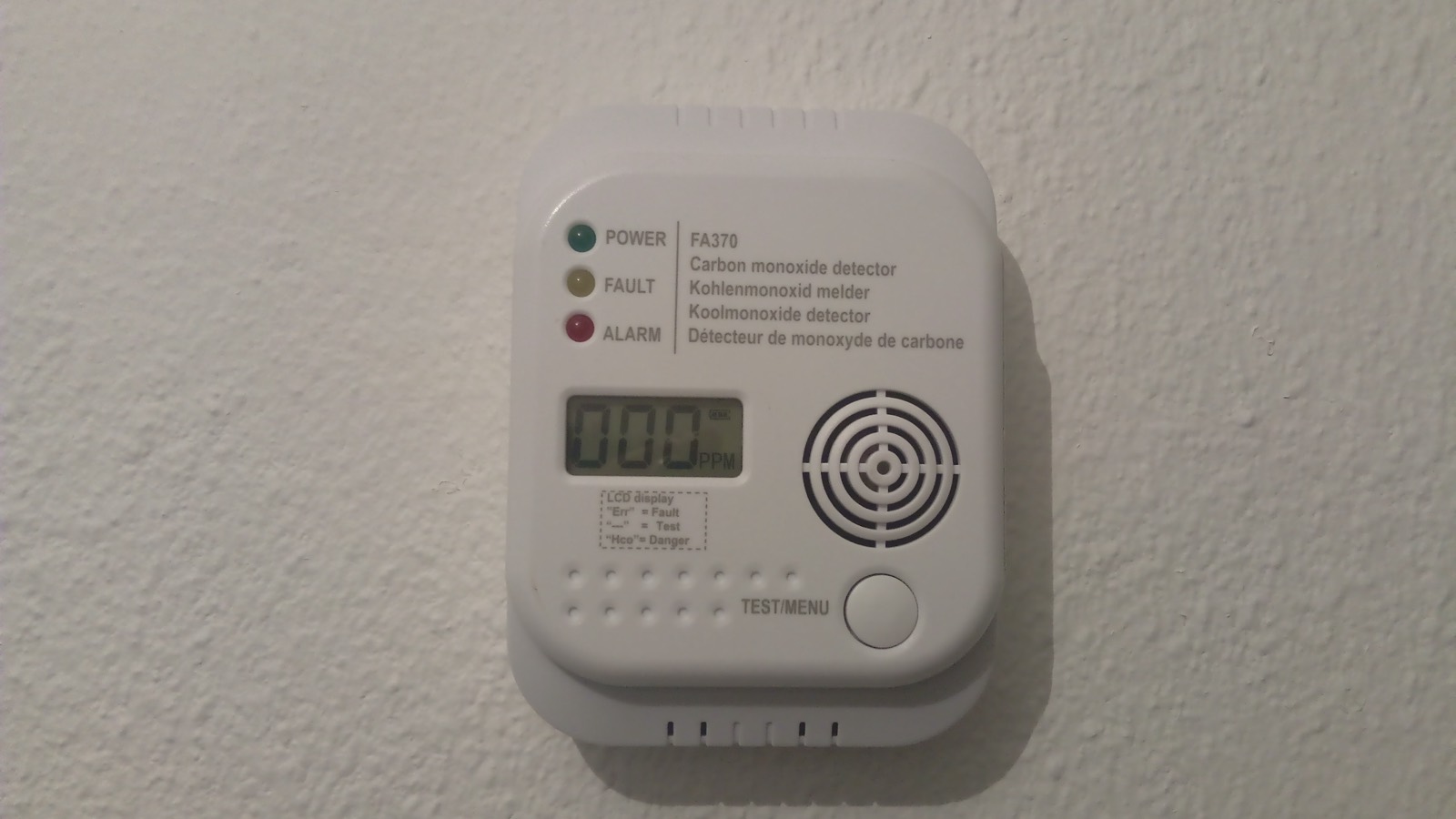 A wall-mounted carbon monoxide detector with a digital display.