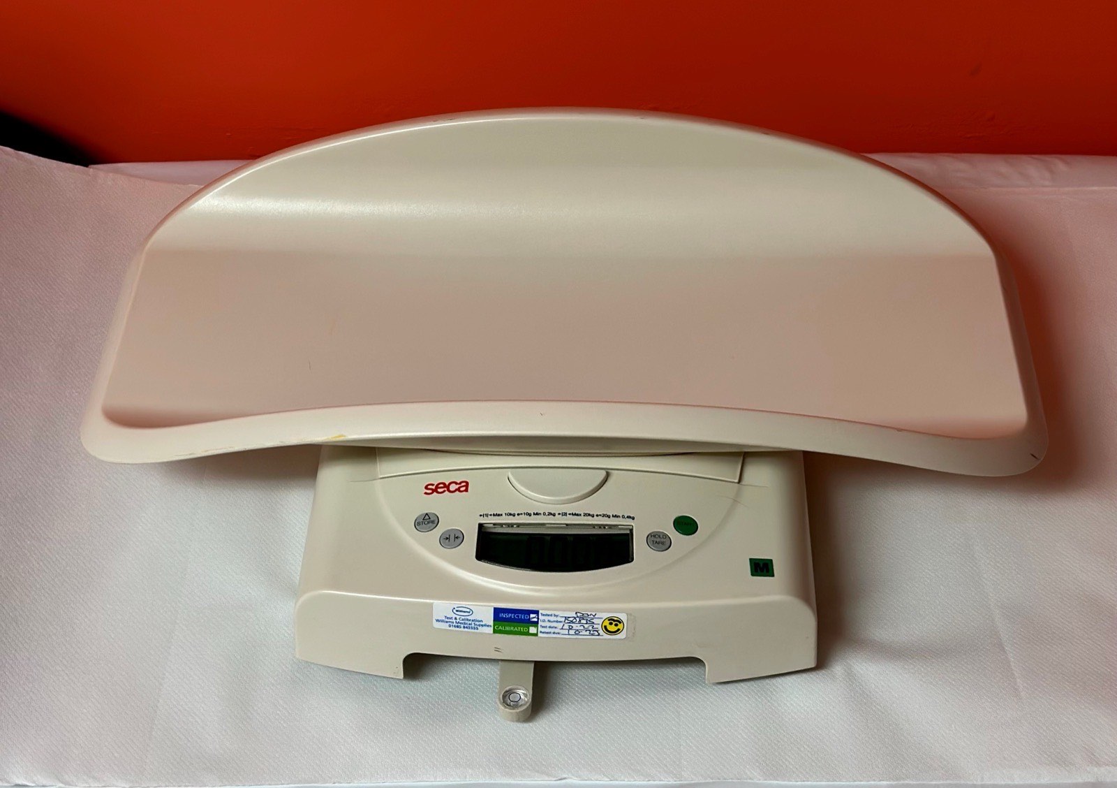 A modern infant weighing scale with a curved tray and digital readout.