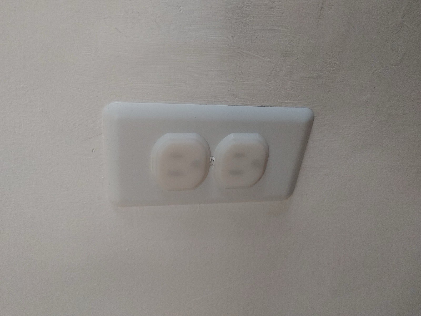 An electrical outlet with two plug-in safety covers in the sockets.