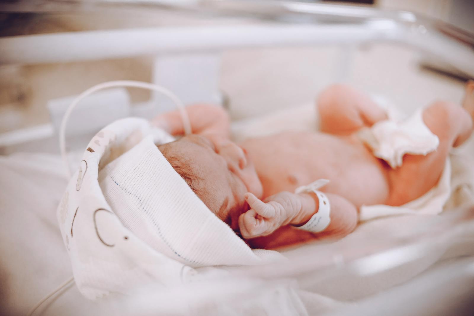 A calm newborn resting, partly wrapped in a soft swaddle.