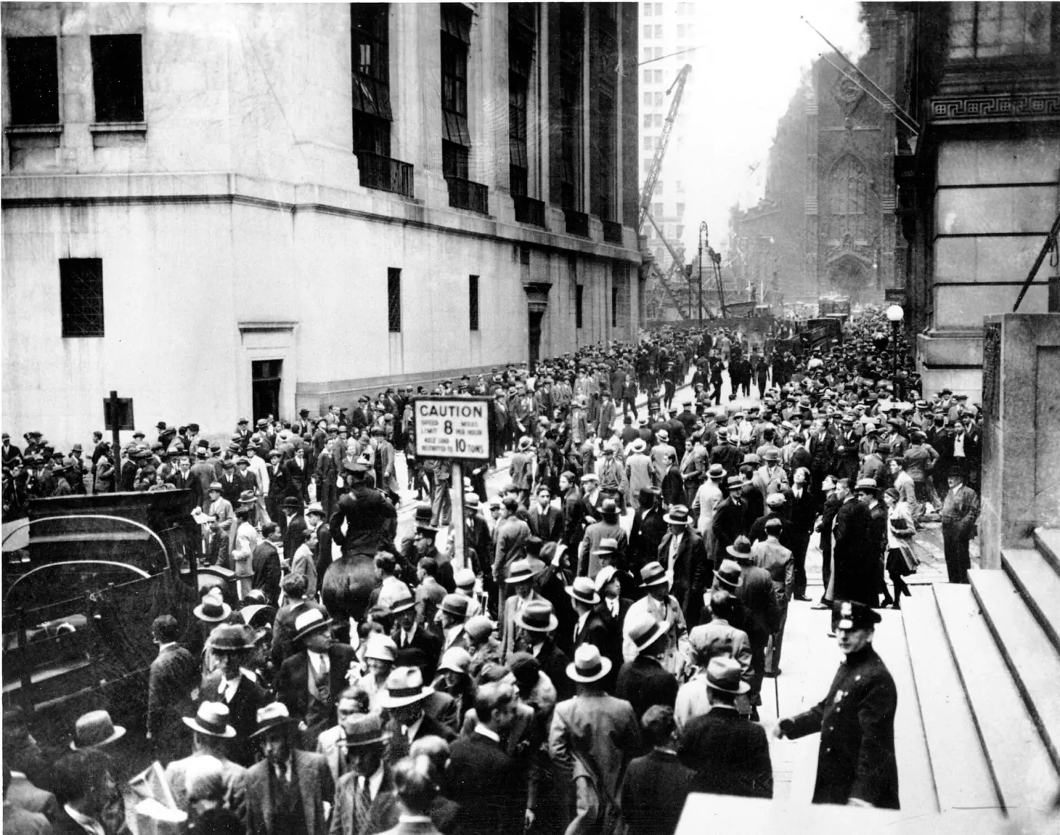 A dense crowd of men in suits and hats filling the street outside the New York Stock Exchange on October 24, 1929.