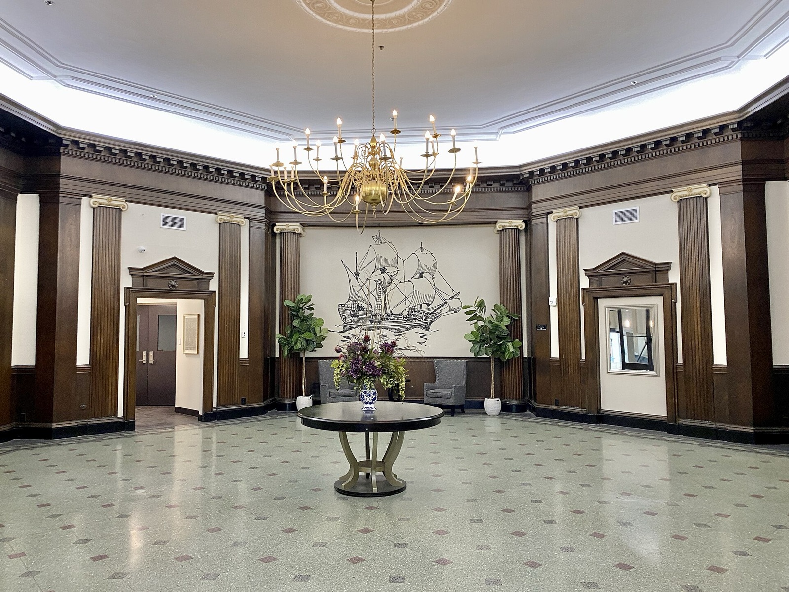 The restored octagonal lobby of the Mayflower Hotel in Akron, with patterned tile, columns, and chandeliers.