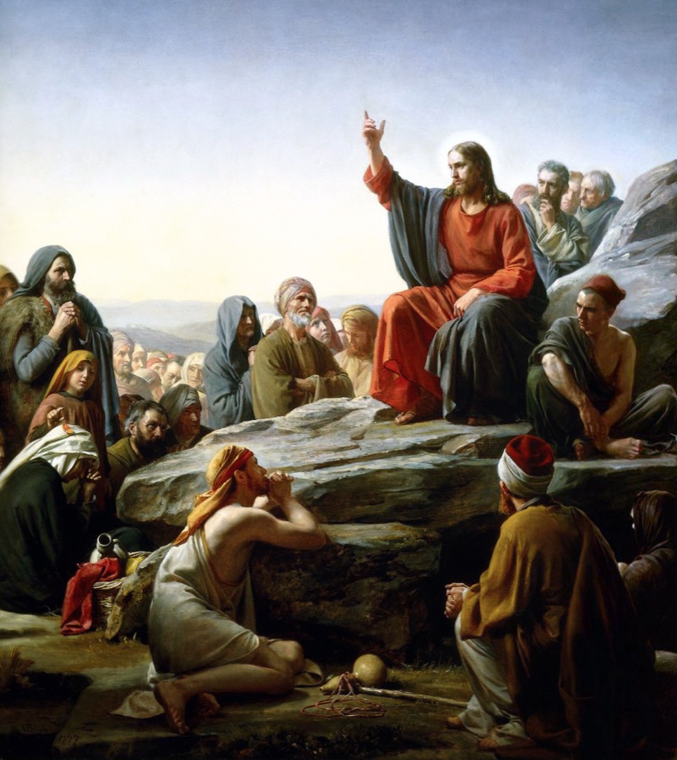 Carl Bloch's 1877 painting: Jesus seated on a rock on a hillside, one hand raised in teaching, a crowd of listeners banked below him against a luminous sky.