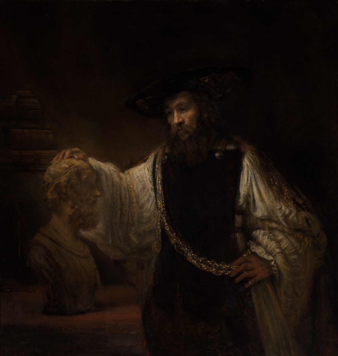 Rembrandt's painting: a bearded Aristotle in a black hat and white sleeves, lit gold against deep shadow, a heavy gold chain across his chest, resting one hand on a pale marble bust of Homer.
