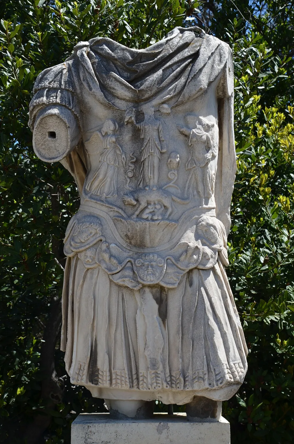 A headless Roman statue wearing a muscle cuirass, a marble breastplate sculpted to look like a bare, idealized muscled torso.