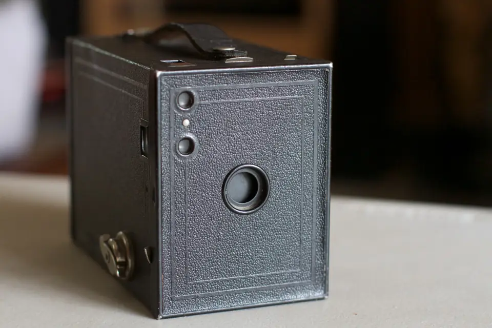 A simple black box Kodak Brownie camera with a small lens, sitting against a plain background.