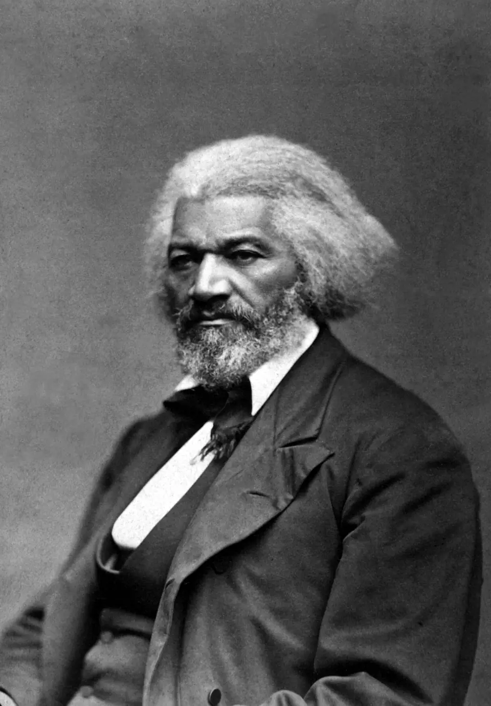 Frederick Douglass around 1879: a formal portrait of Douglass with white hair, set jaw, and a direct, unsmiling gaze.