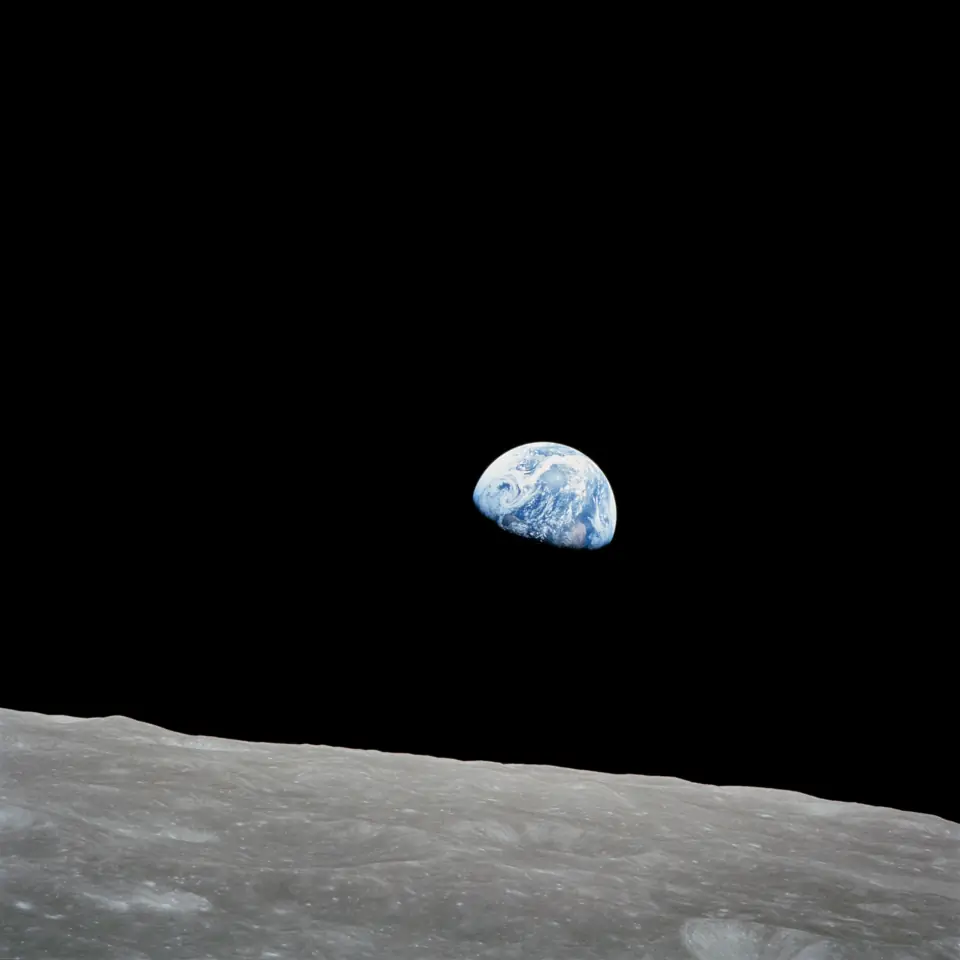 Earthrise: the blue and white Earth rising over the gray lunar horizon, photographed from Apollo 8.