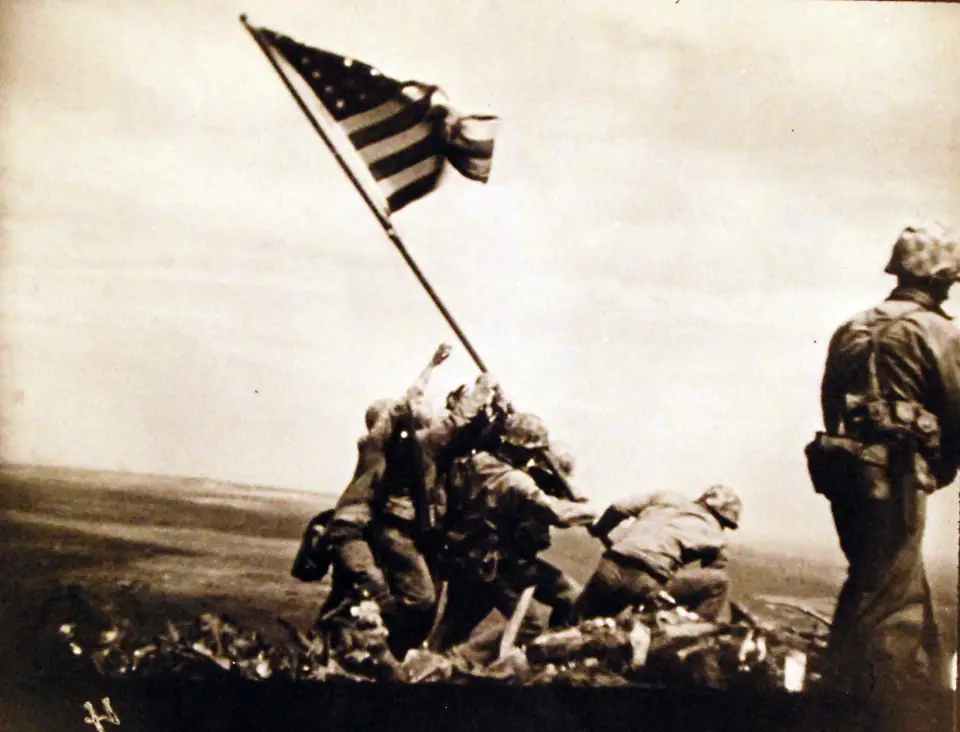 A color film frame of the second flag raising on Iwo Jima: Marines planting the flagpole on Mount Suribachi.
