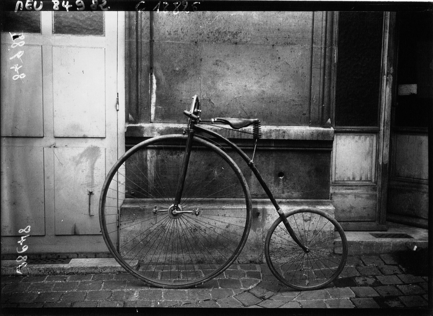 A vintage high-wheel penny-farthing bicycle with its enormous front wheel and tiny rear wheel.