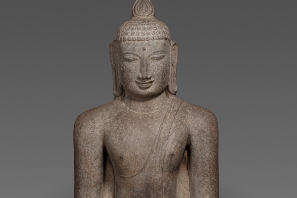 A Chola-period granite statue of the Buddha seated in meditation, eyes lowered and serene, hands resting cupped in his lap in the dhyana mudra.